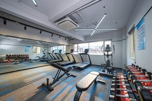 Un gimnasio con cintas de correr, elípticas y bancos de pesas.