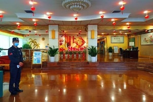 A hotel lobby with a polished floor, red lanterns, and a large decorative entrance.