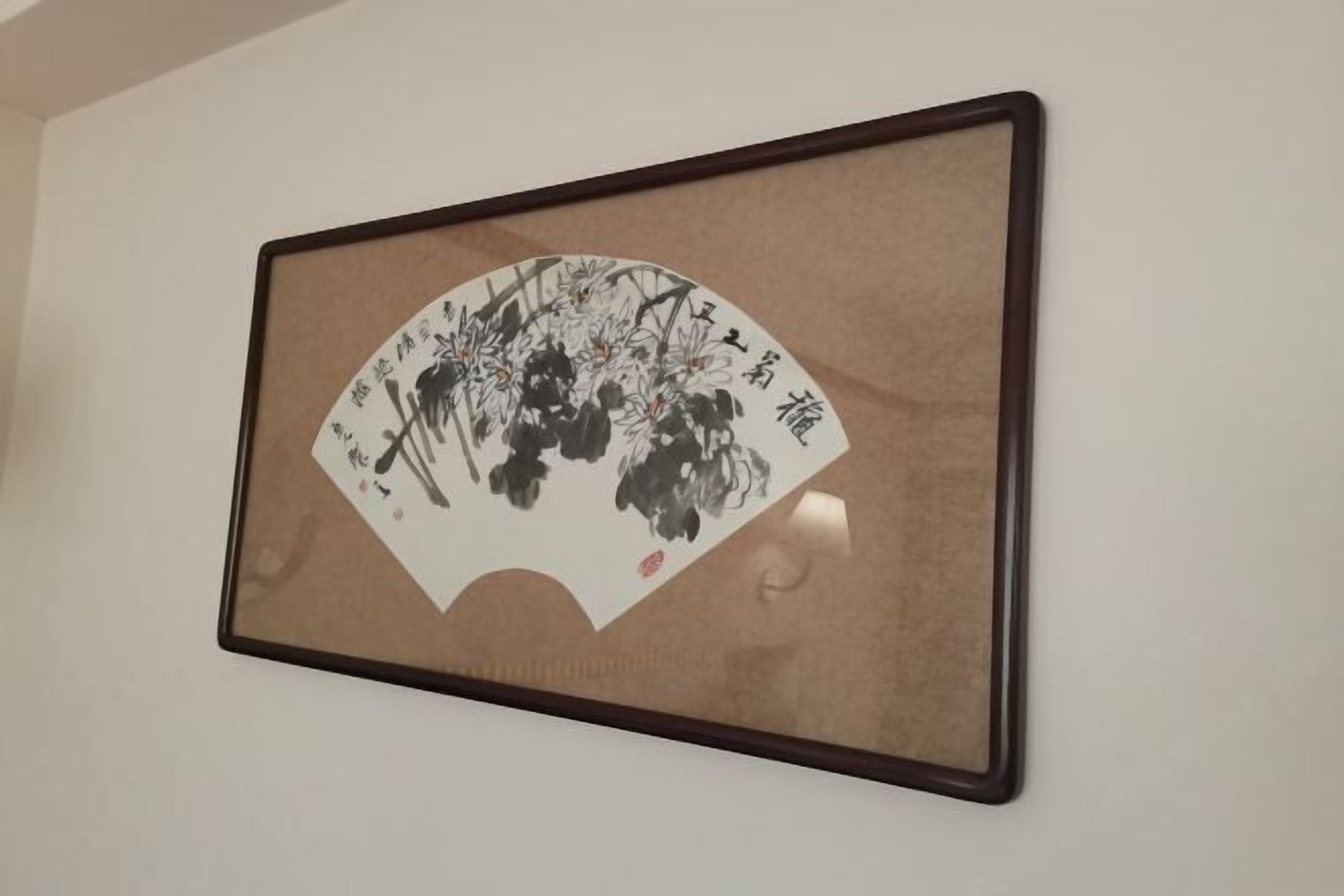 A framed artwork with calligraphy and floral designs on a wall.