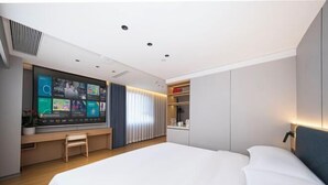 A modern hotel room with a large bed, a TV mounted on the wall, a small seating area, and a built-in shelf. - Fuchun Hotel (Fu'an)