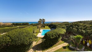 A landscaped garden with a swimming pool, palm trees, and a view of the sea. - Residence Punta Cassano - Fronte Mare PP (Melendugno)