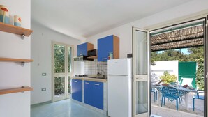 Eine moderne Küche mit blauen Schränken, einem weißen Kühlschrank und einem Essbereich mit blauen Stühlen und einem Tisch.