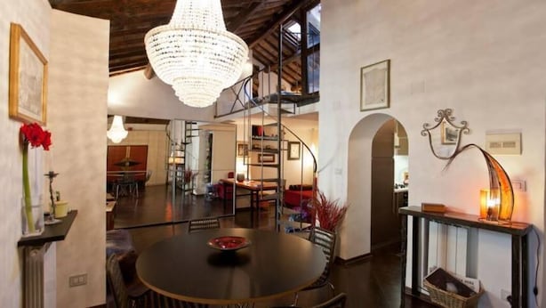 A spacious dining area with a chandelier, a spiral staircase, and a view of the kitchen. - Loft on Via dei Cappellari, near Campo de' Fiori (Rome)