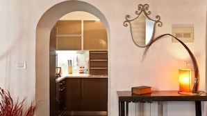 An interior view of a hotel room with a kitchenette, a mirror, and a lamp on a console table. - Loft on Via dei Cappellari, near Campo de' Fiori (Rome)