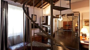 A spiral staircase in a room with a leather sofa, a lamp, and framed pictures on the walls. - Loft on Via dei Cappellari, near Campo de' Fiori (Rome)