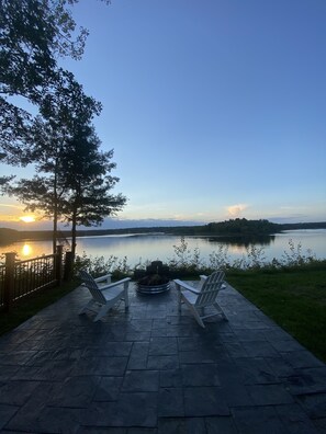 A patio with two Adirondack chairs facing a lake at sunset. - Tranquility on Rogers Pond (Stanwood)