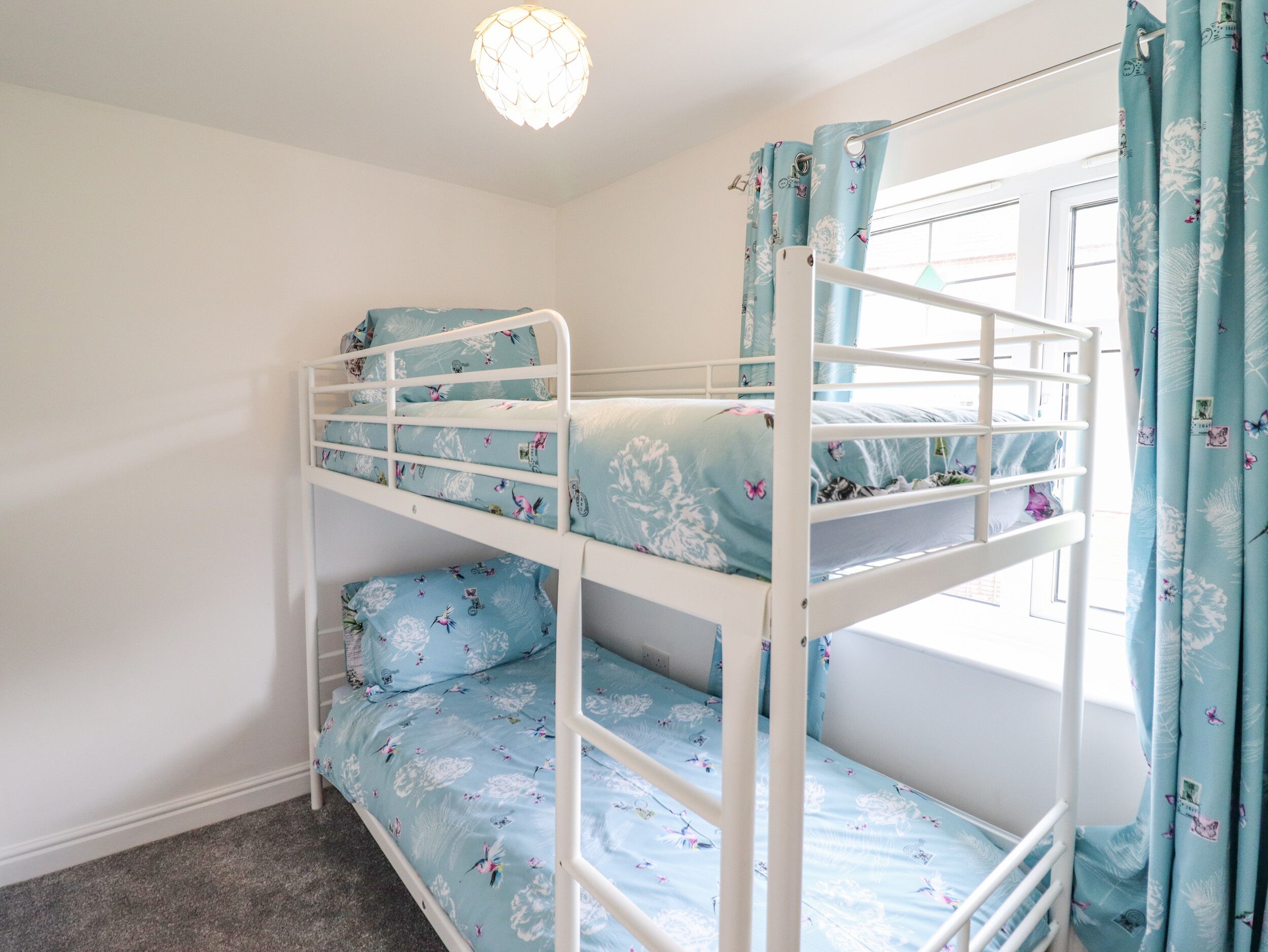 A bunk bed room with a window and curtains.