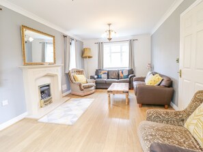 A living room with a fireplace, a sofa, a chair, and a coffee table. - Pencraig (Colwyn Bay)
