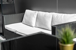 A modern room with a black wicker sofa, white cushions, and a small potted plant. - Stunning Two Bed Penthouse - Large Private Terrace - Parking (Birmingham)