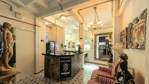 Een hotellobby met een receptiebalie, een standbeeld, een bank en een kroonluchter.