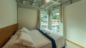 Een hotelkamer met een bed, een raam met gordijnen en uitzicht op gebouwen.