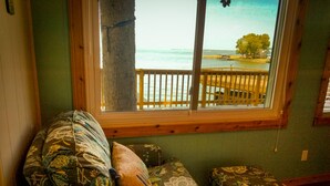 Une pièce avec vue sur la mer, donnant sur un balcon avec une rambarde en bois.