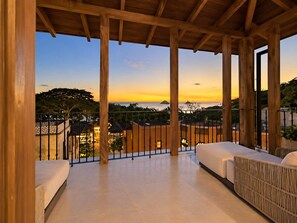 A covered outdoor area with a view of the sea and buildings.