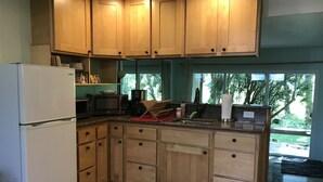 Una cocina con armarios de madera, un refrigerador, un microondas y una cafetera.