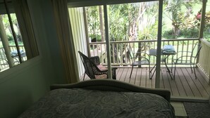 Un dormitorio con cama, ventana y vista a un balcón exterior con sillas y una mesa.