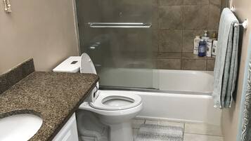 Et badeværelse med bruser, toilet og håndvask.
