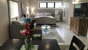 A bedroom with a bed, bedside tables, a TV, and a dining area with a table and chairs.