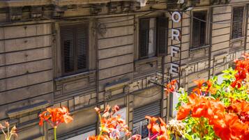 A building facade with multiple windows, some with shutters, and a sign that reads "ORE".