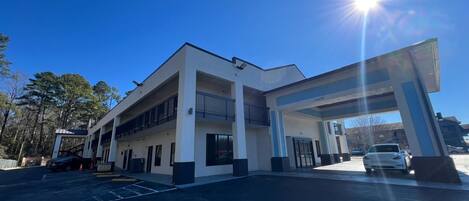 A modern building with a gas station, multiple parking spaces, and a clear sky.