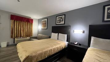 Une chambre d’hôtel avec un grand lit, deux tables de chevet, une chaise, un bureau et une fenêtre avec des rideaux.