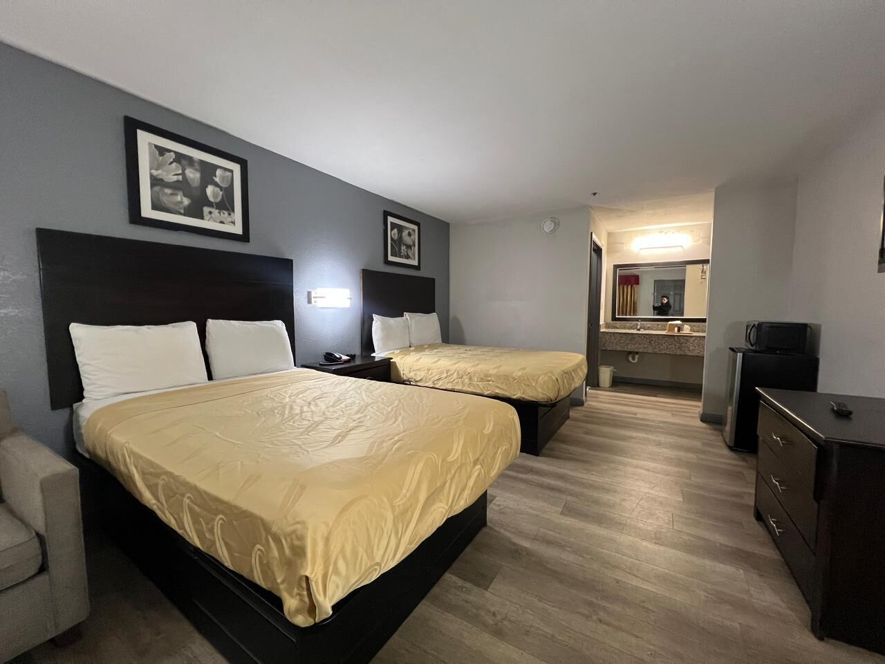 Habitación de hotel con dos camas, un escritorio, una silla, un aparador y un espejo.