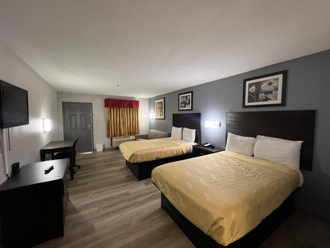Ein Hotelzimmer mit zwei Betten, einem Schreibtisch, einem Stuhl, einem Fernseher und einer Tür.