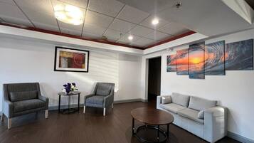 A modern living room with a grey sofa, two armchairs, a coffee table, and artwork on the walls.