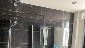 A modern bathroom with a glass-enclosed shower, a white sink, and a mirror above it.