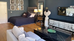A bedroom with a bed, a nightstand, a dresser, a mirror, a sofa, and a coffee table.
