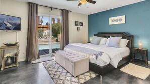 A bedroom with a bed, a ceiling fan, a nightstand, a bedside table, and a view of a pool. - Tranquil Padua Pad - A Ryson Property (Palm Springs)
