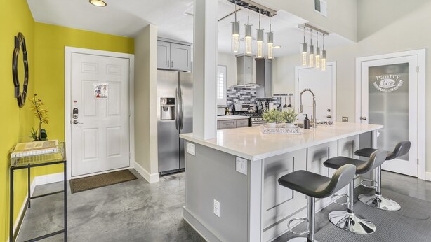A modern kitchen with a central island, bar stools, stainless steel appliances, and pendant lighting. - Tranquil Padua Pad - A Ryson Property (Palm Springs)