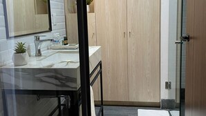 A modern bathroom with a glass shower enclosure, a wooden vanity, and a large mirror. - Exclusive 409 (Aguascalientes)