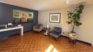 A living room with a coffee machine, two armchairs, a side table, a framed picture, and a potted plant. - Exclusive 409 (Aguascalientes)