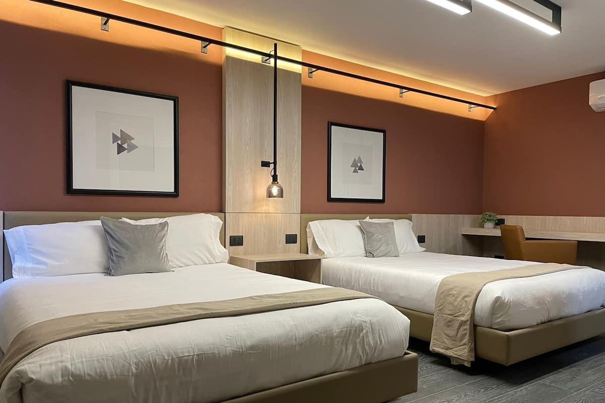 Une chambre d’hôtel avec deux lits, un bureau et une chaise.