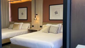 A hotel room with two beds, a large mirror, and framed artwork on the walls.