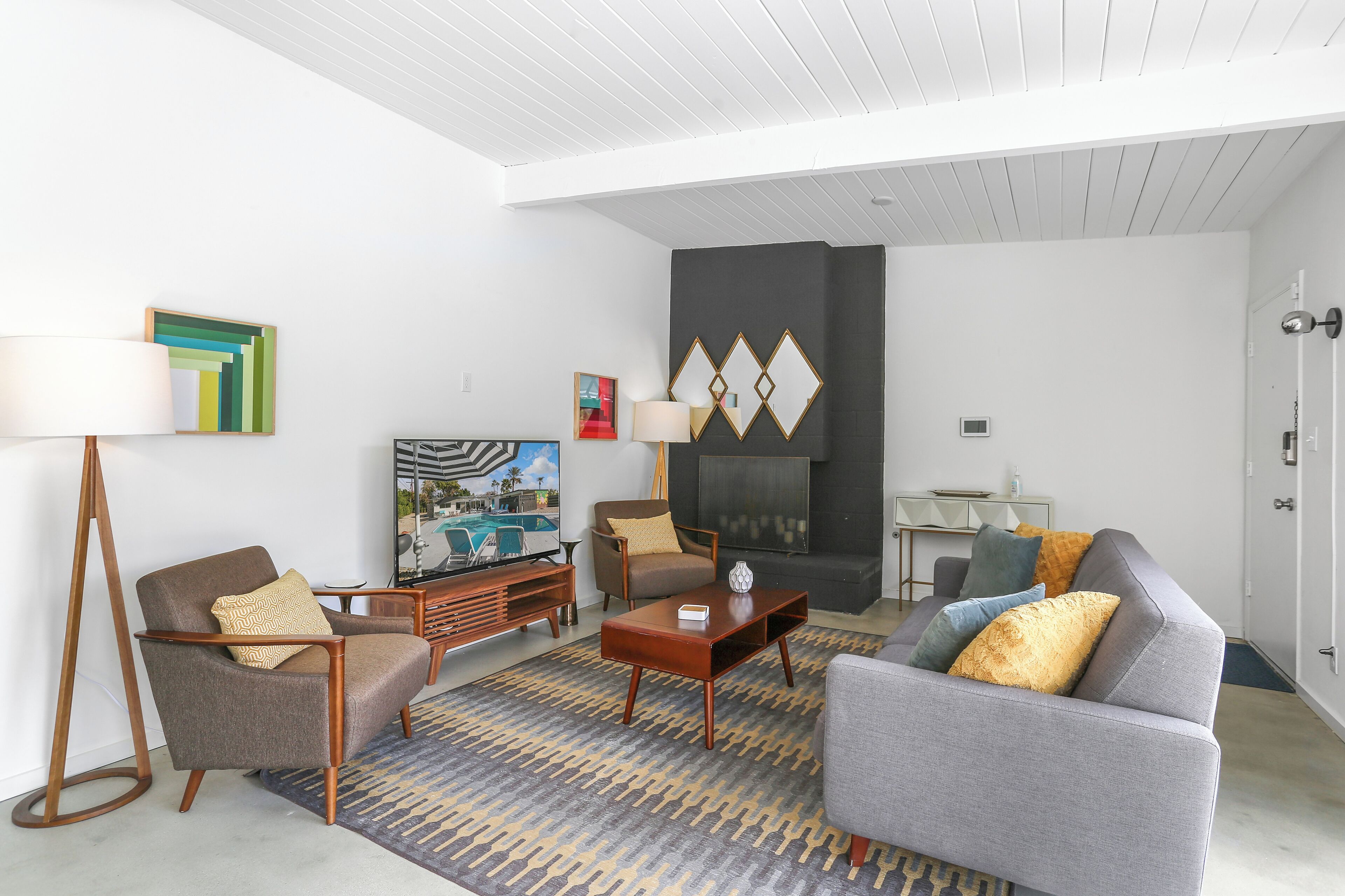 A modern living room with a sofa, armchairs, a coffee table, and a TV.