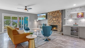Un salon moderne avec un canapé, des fauteuils, un téléviseur et une cheminée.
