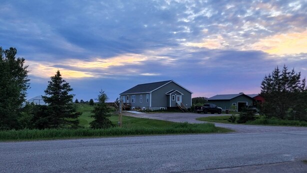 A residential area with houses, a paved road, and a grassy field. - Country, close to town, sled trails, skiing, large snowmobile boat trailer space (Sault Ste. Marie)