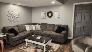 A living room with a sectional sofa, a coffee table, a floral rug, and decorative wall art. - Country, close to town, sled trails, skiing, large snowmobile boat trailer space (Sault Ste. Marie)