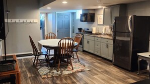 A modern kitchen with a dining area, wooden flooring, and a refrigerator. - Country, close to town, sled trails, skiing, large snowmobile boat trailer space (Sault Ste. Marie)