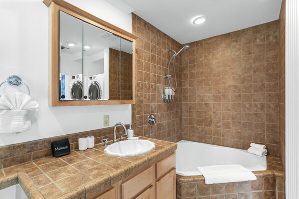 A bathroom with a sink, mirror, and shower.