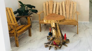 Una silla y una mesa de madera con base de tocón de árbol, una planta en maceta y un cuadro de una playa en la pared.