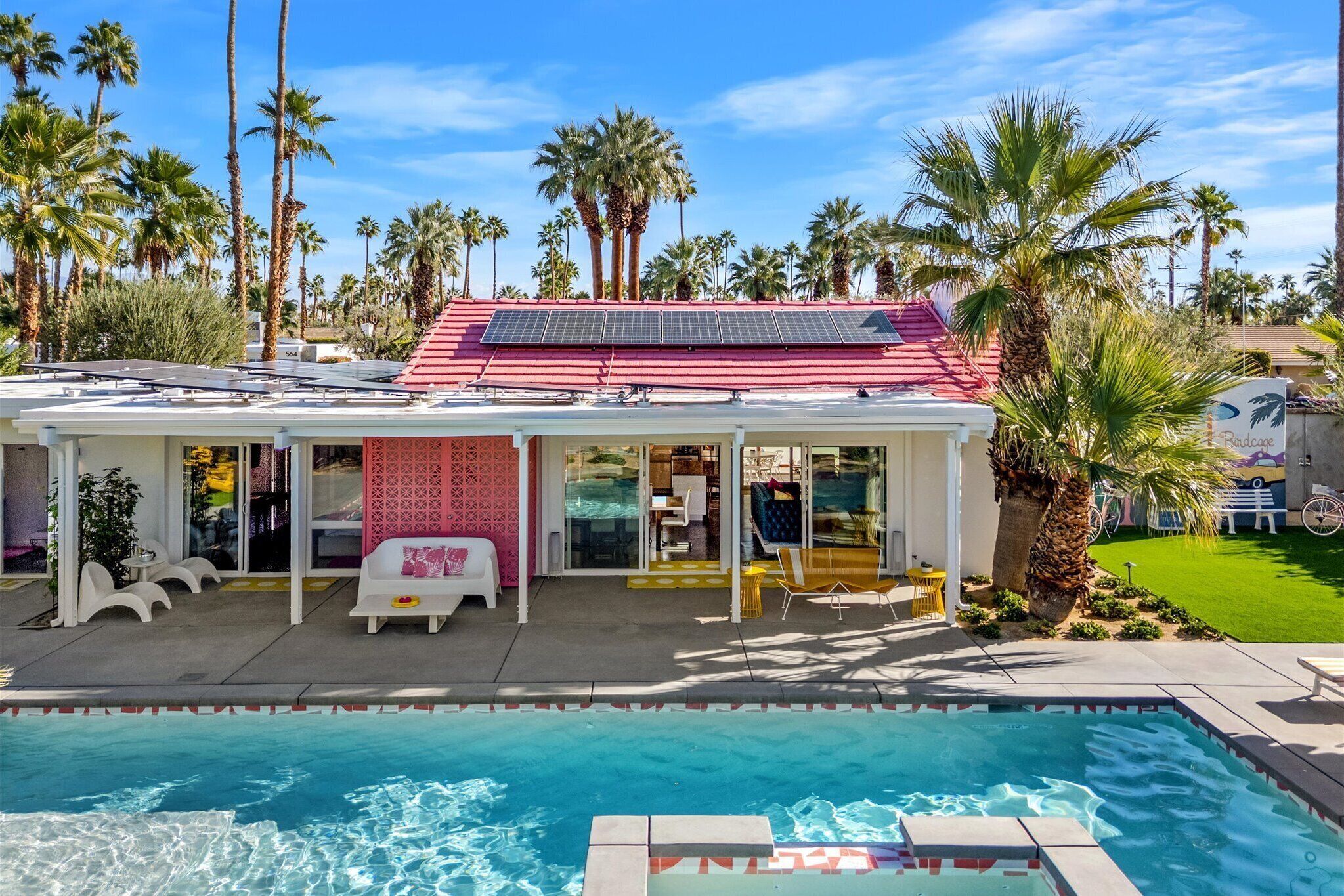 A poolside building with a red roof, solar panels, and a pool.