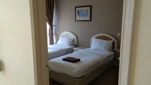 A hotel room with two single beds, a framed picture on the wall, and a brown item on the bed. - OYO Home 90533 Nomadic Town Condo (Malacca City)