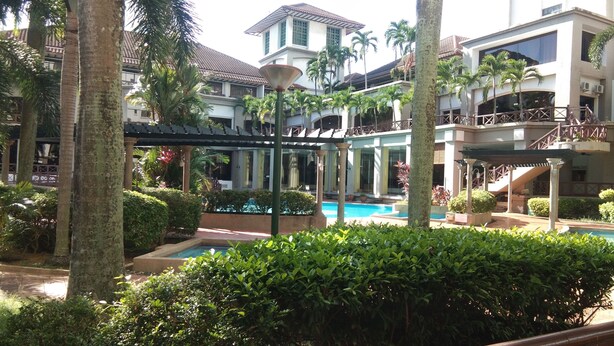 A resort with a swimming pool, palm trees, and a covered walkway. - OYO Home 90533 Nomadic Town Condo (Malacca City)