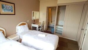 A hotel room with two beds, a desk, a chair, a bathroom with a shower, and a door leading to another room. - OYO Home 90533 Nomadic Town Condo (Malacca City)