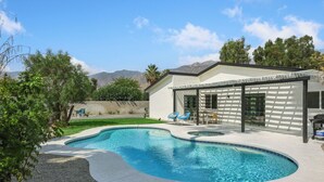 A modern house with a swimming pool, a covered patio, and a view of mountains. - Desert Green Serenity - A Ryson Property (Palm Springs)