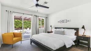 A bedroom with a bed, a nightstand, a lamp, a chair, and a ceiling fan. - Tangerine Desert Dreams - A Ryson Property (Palm Springs)
