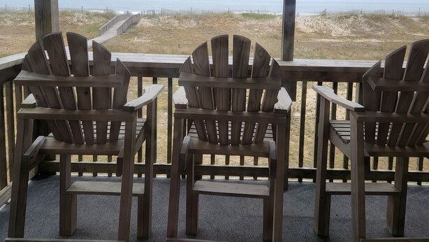 Un espacio al aire libre cubierto con sillas de madera y vista a la playa.