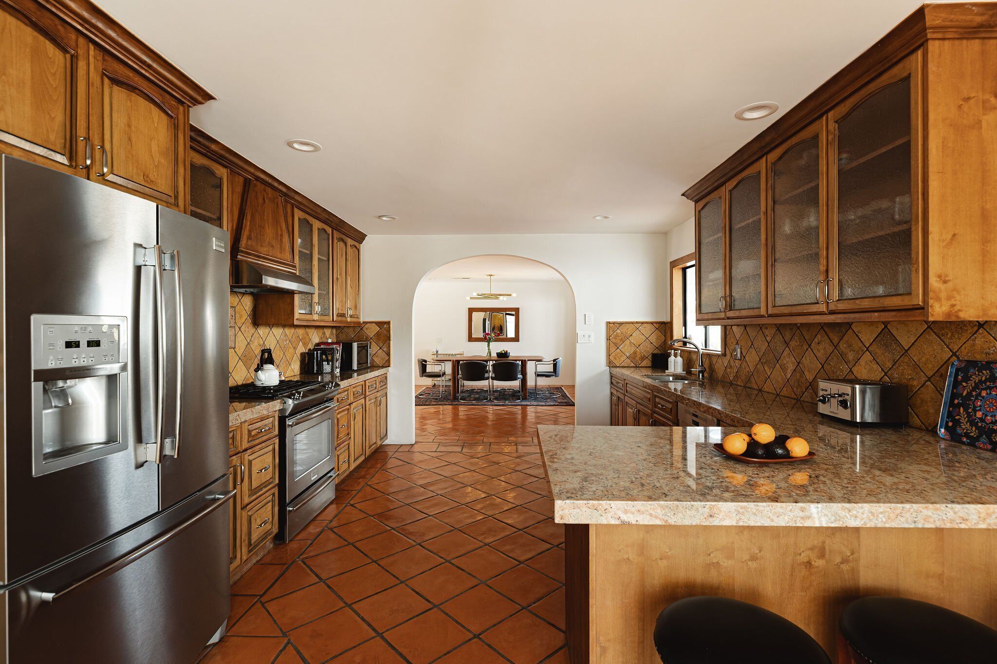 A kitchen with wooden cabinets, stainless steel appliances, and a tiled floor.